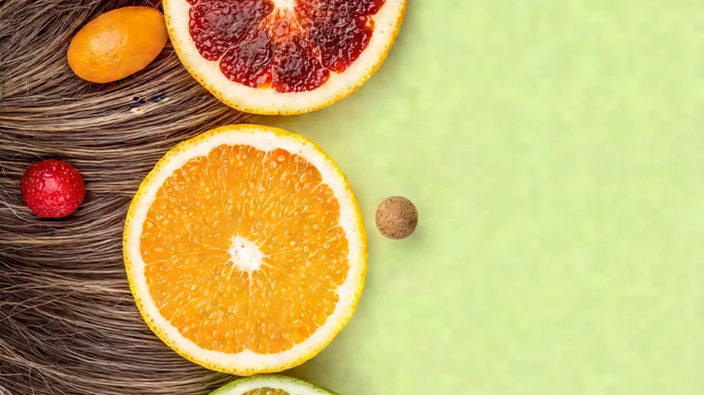 A vibrant composition featuring a variety of fresh fruits, including sliced oranges, blood oranges, and kumquats, arranged artistically on a background of silky, healthy hair. The image symbolizes the importance of consuming vitamin-rich fruits for hair health and addressing hair loss. The citrus fruits highlight the benefits of Vitamin C and other essential nutrients for strengthening hair and promoting growth.